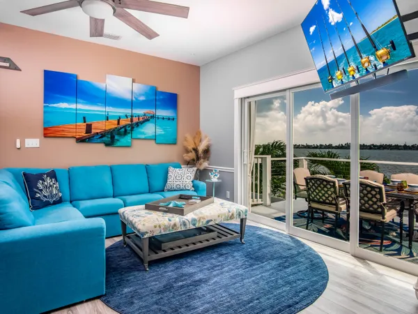 a living room with furniture a flat screen tv and a floor to ceiling window