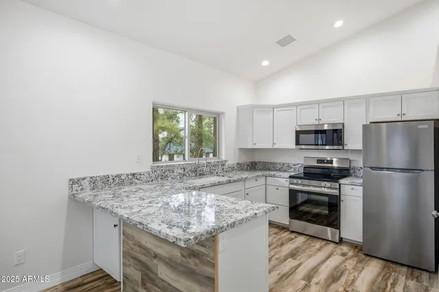 a view of kitchen and empty room with wooden floor