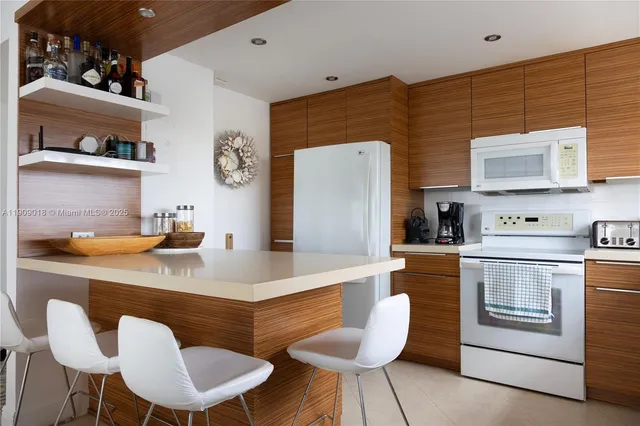 a kitchen with stainless steel appliances granite countertop a table chairs stove and refrigerator