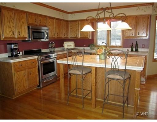 13331 Cathy Lane Plainfield, IL 60585 - Photo 4 of 16 a kitchen with stainless steel appliances granite countertop a stove top oven a sink a dining table and chairs with wooden floor