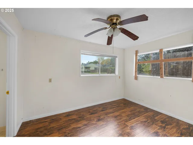 a view of empty room with wooden floor and fan