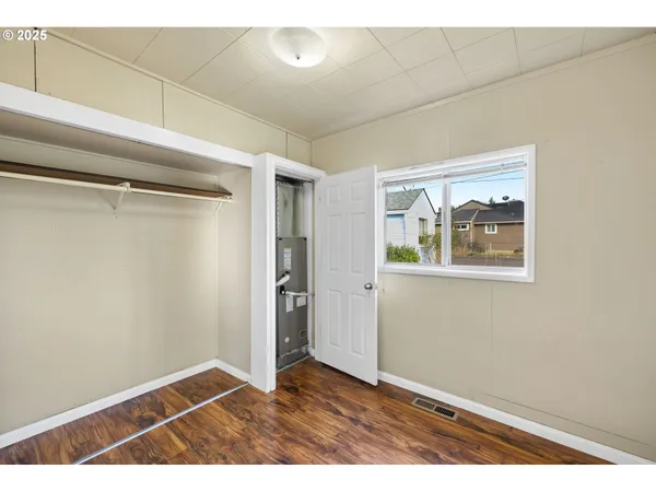 a view of an empty room with closet and a window