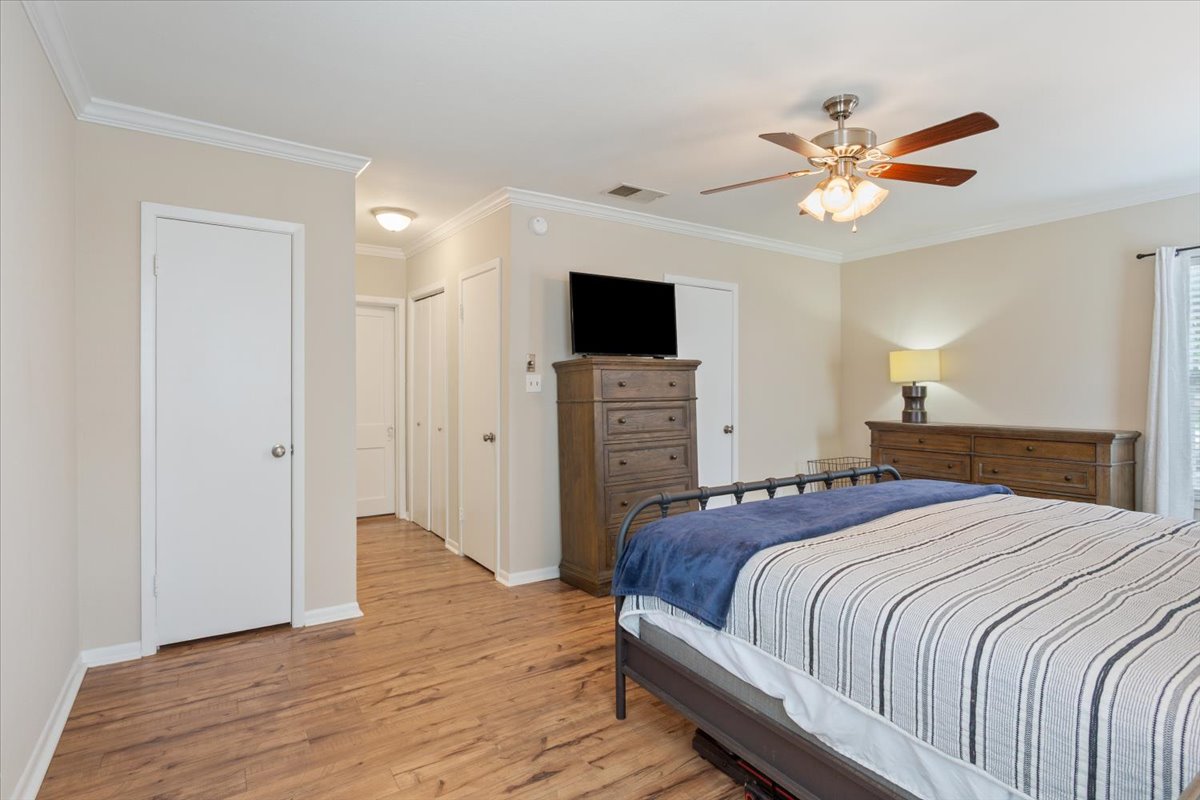 1607 North Harding Avenue Cameron, TX 76520 - Photo 17 of 37 Well-lit sleeping quarters with a ceiling fan, crown molding, and beautiful hardwood flooring.