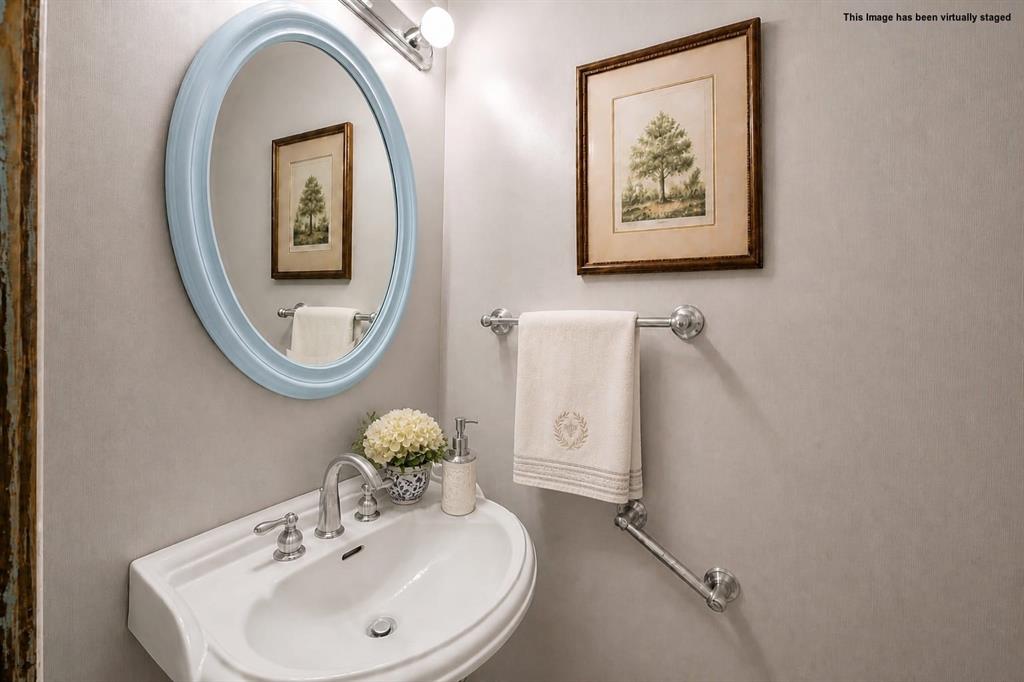 608 West Spring Street West, TX 76691 - Photo 19 of 23 Wall-mounted porcelain sink with chrome fixtures, oval framed mirror, and a wall-mounted towel bar