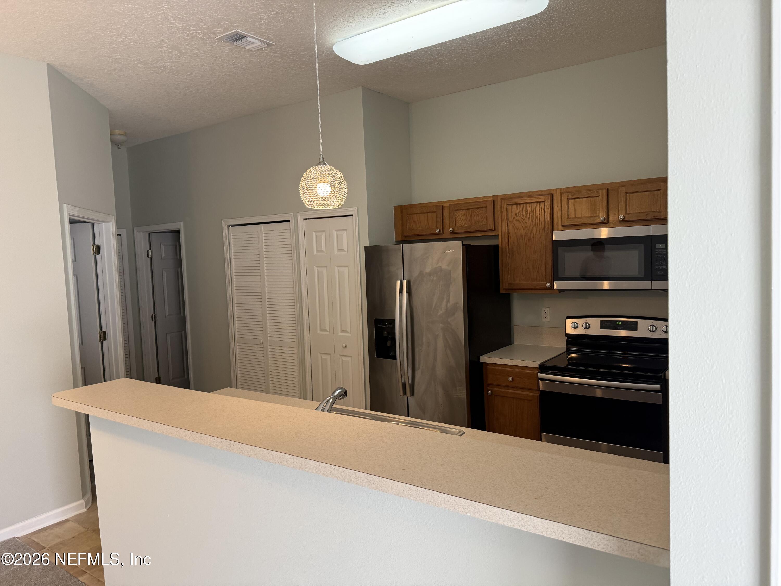 7920 Merrill Road, Unit 403 Jacksonville, FL 32277 - Photo 15 of 18 a kitchen with stainless steel appliances a refrigerator and microwave