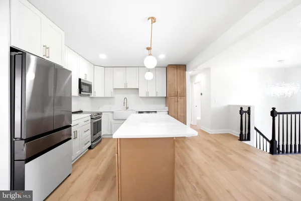 a kitchen with stainless steel appliances granite countertop a refrigerator a sink dishwasher a stove and a refrigerator with wooden floor
