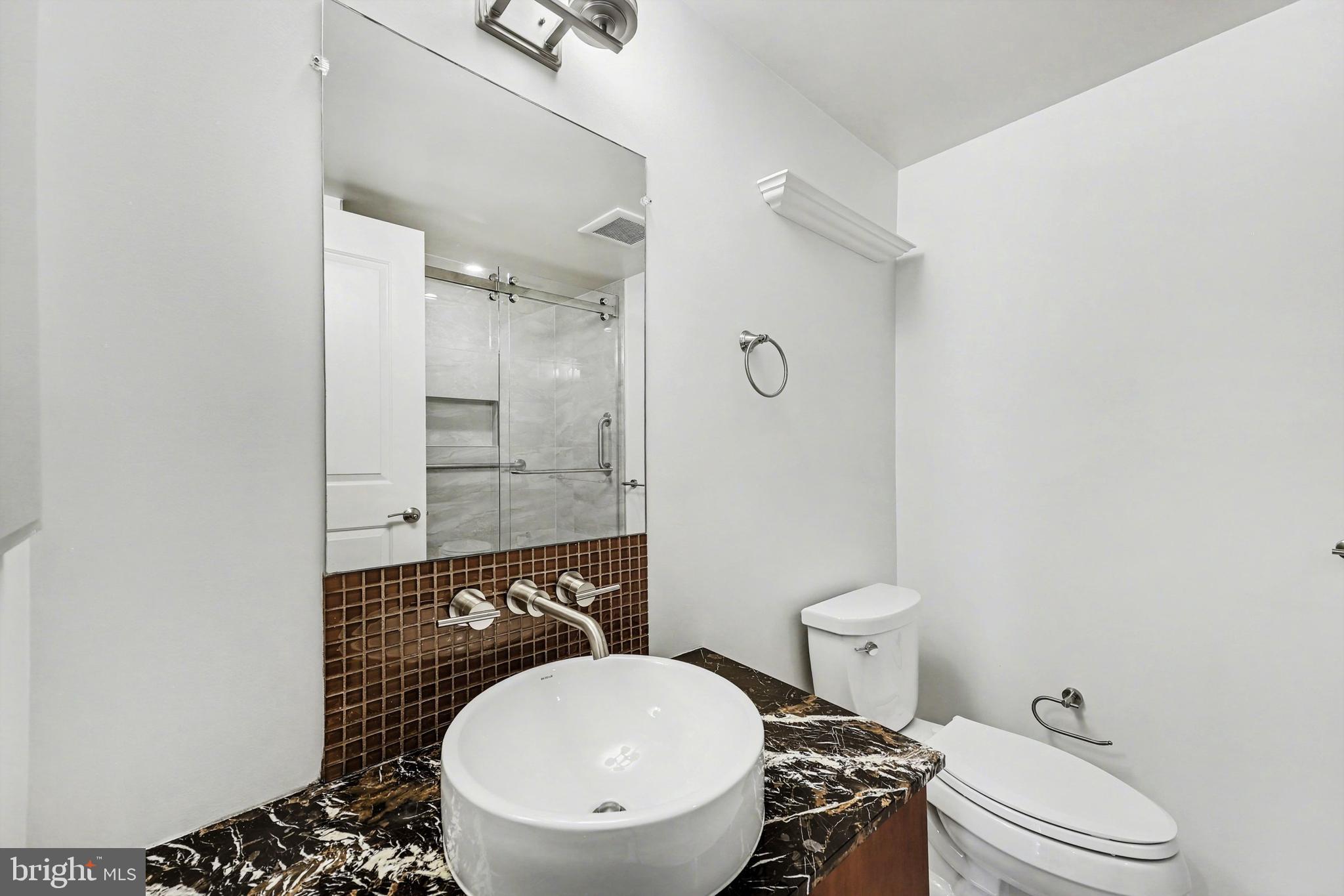 1025 First Street Southeast, Unit 906 Washington, DC 20003 - Photo 19 of 34 a bathroom with a toilet a sink and mirror