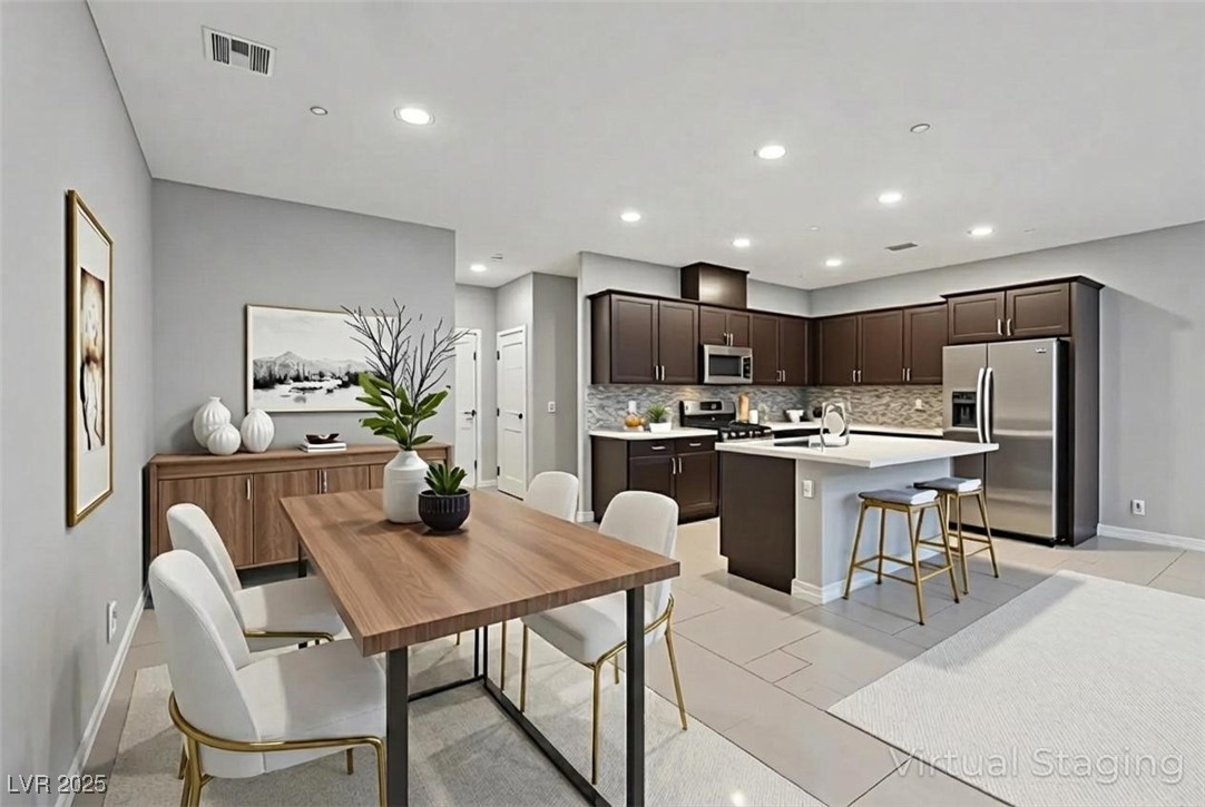 143 Aqua Commons Lane Henderson, NV 89015 - Photo 7 of 20 Kitchen featuring dark brown cabinetry, appliances with stainless steel finishes, a kitchen breakfast bar, an island with sink, and recessed lighting