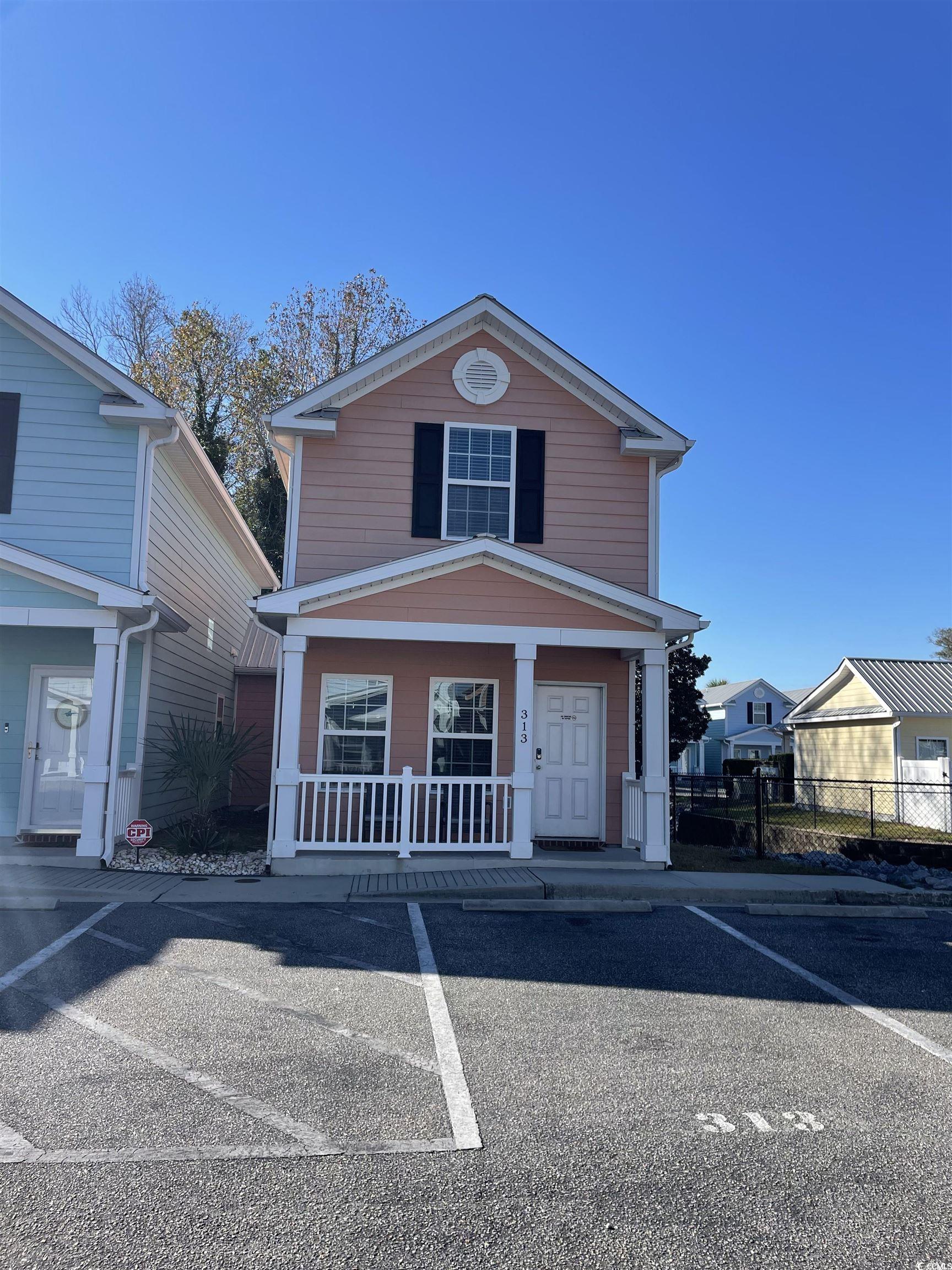 View of front of property with a porch and uncovered parking