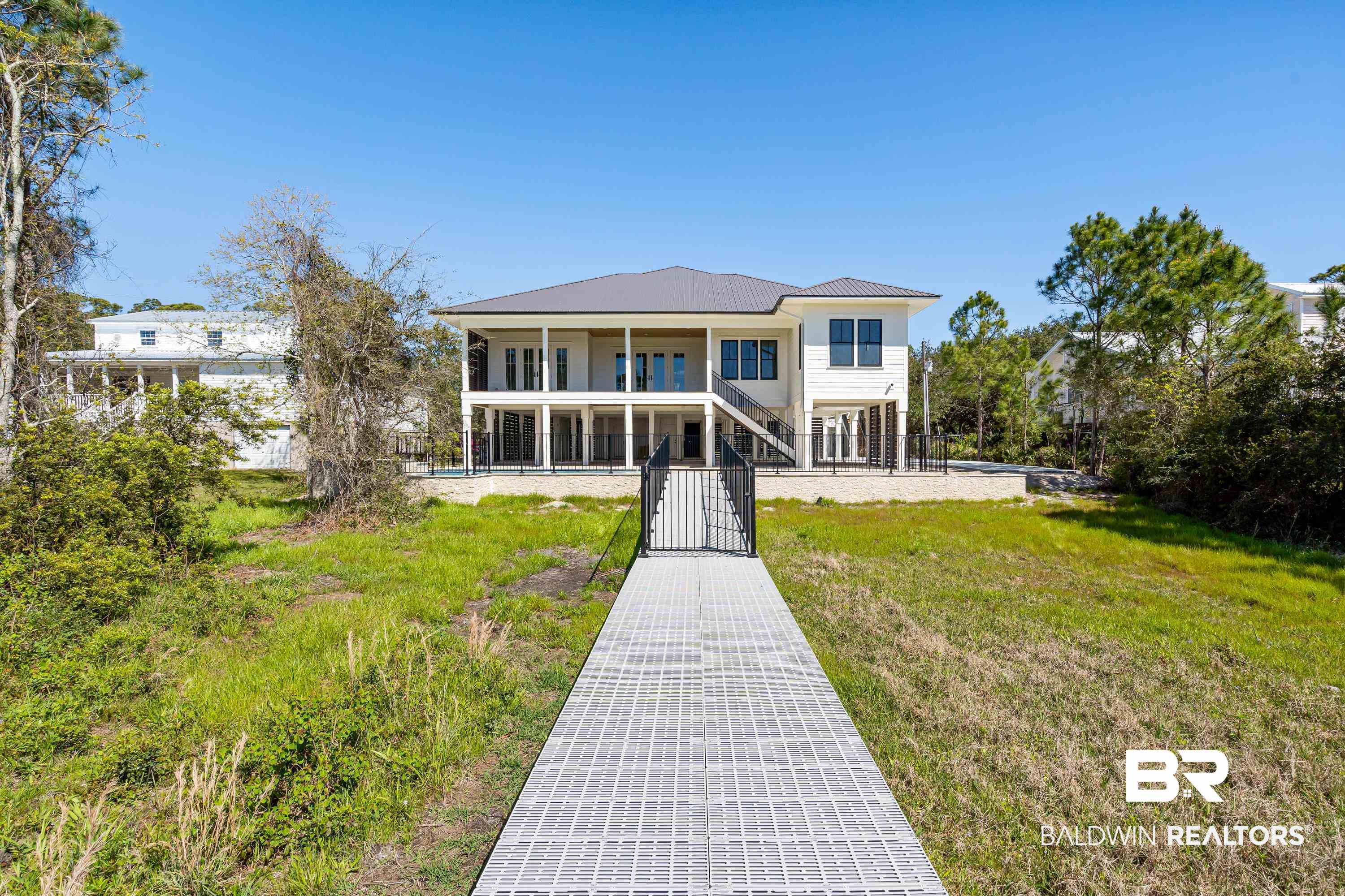 14686 State Highway Gulf Shores, AL 36542 - Photo 31 of 44 Back of house featuring a fenced front yard, stairway, and a lawn