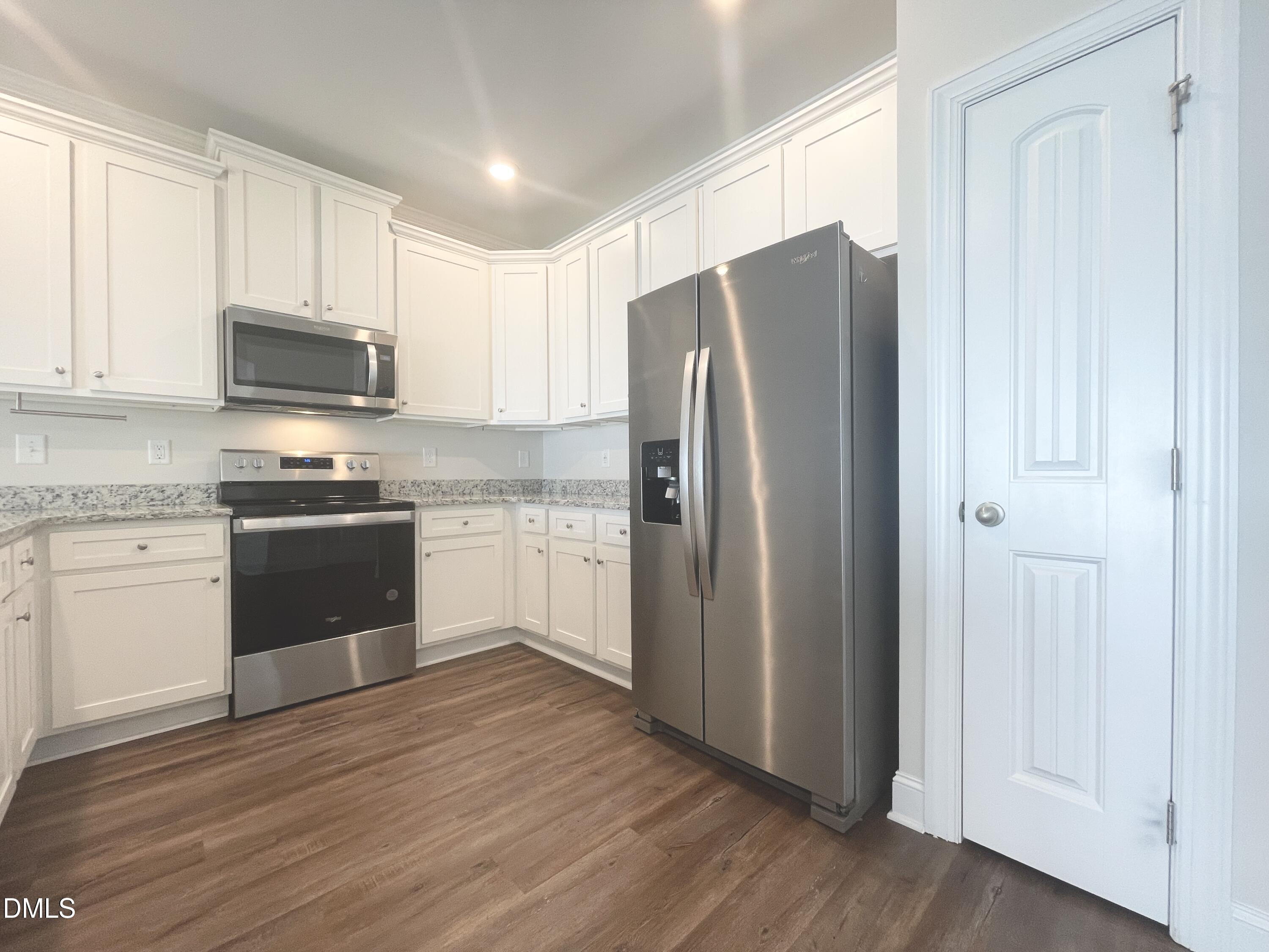 6945 Outfall Point Lane Raleigh, NC 27616 - Photo 4 of 23 a kitchen with a refrigerator sink and white cabinets
