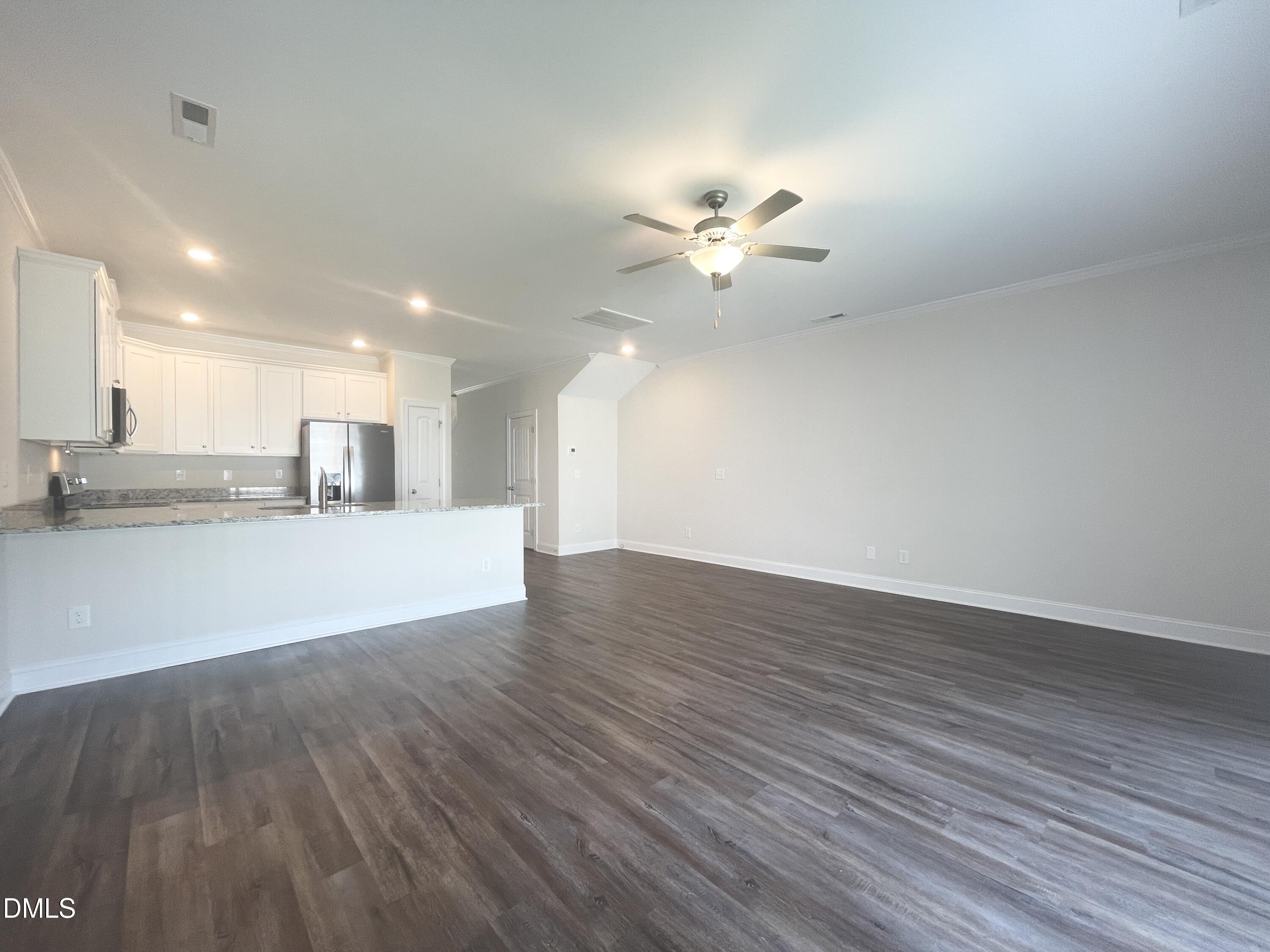 6945 Outfall Point Lane Raleigh, NC 27616 - Photo 7 of 23 a view of an empty room and kitchen with wooden floor