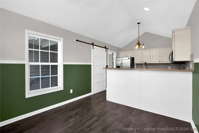 a kitchen with stainless steel appliances granite countertop a refrigerator a sink a stove and a wooden floors