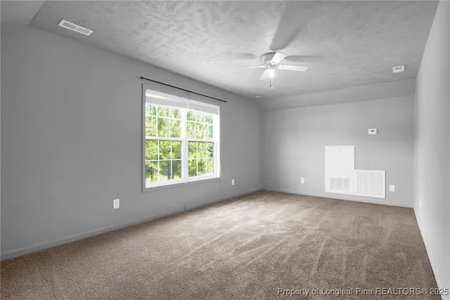 an empty room with a ceiling fan and window