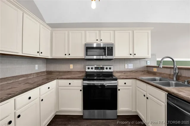 a kitchen with granite countertop white cabinets and stainless steel appliances