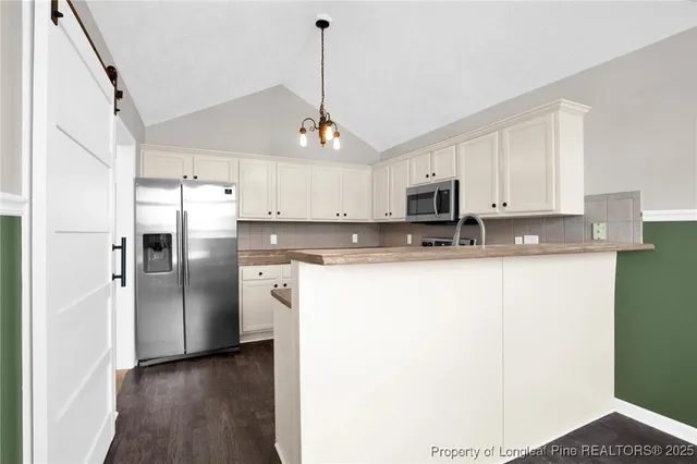 a kitchen with stainless steel appliances granite countertop a refrigerator a stove a sink and a microwave