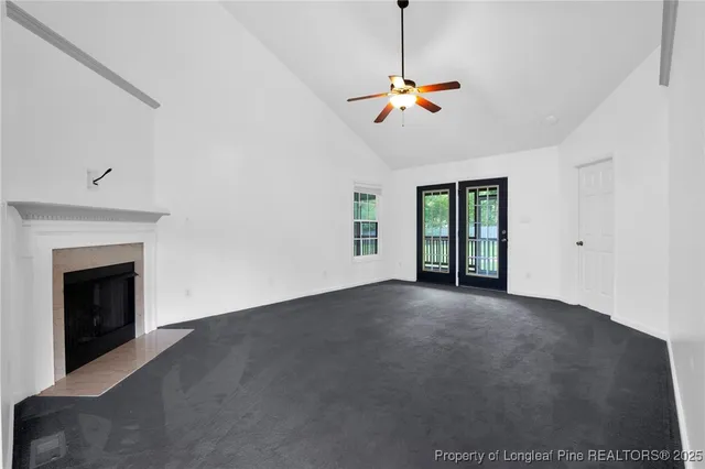a view of an empty room with chandelier fan and fire place