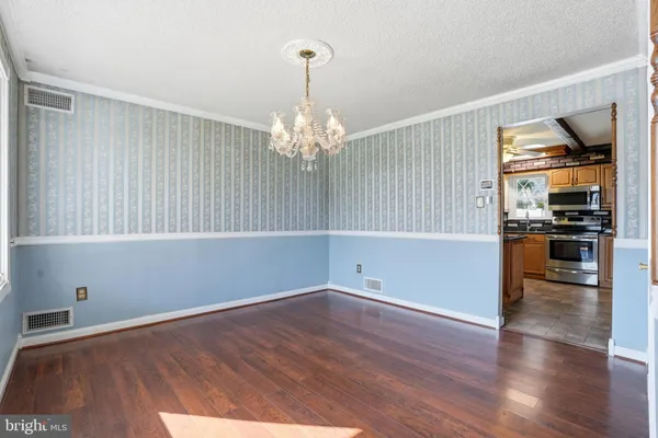a view of empty room with wooden floor and kitchen view