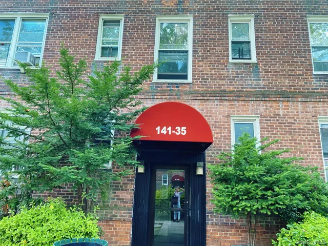 a view of a brick house with a large windows and flower plants
