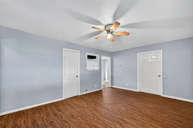 a view of an empty room with window and wooden floor