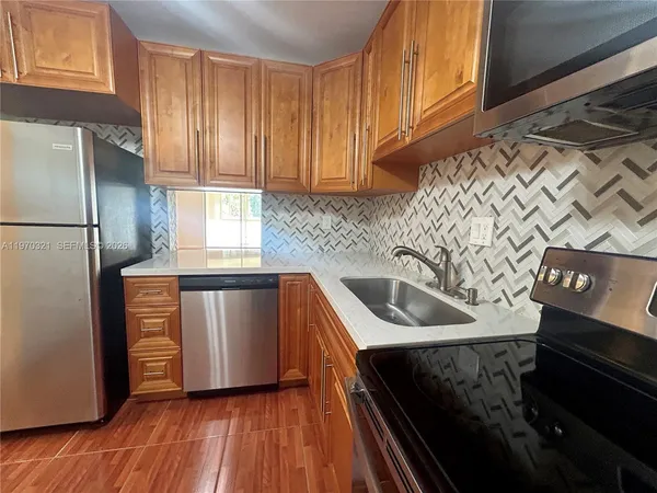 a kitchen with stainless steel appliances granite countertop a refrigerator a sink dishwasher a stove with wooden cabinets and floor