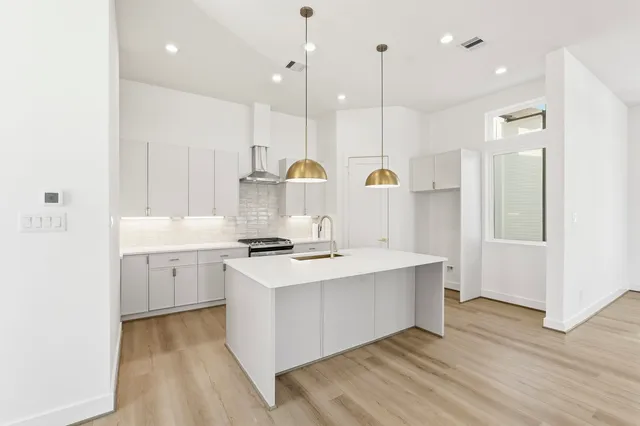 a kitchen with a sink a stove a refrigerator and white cabinets