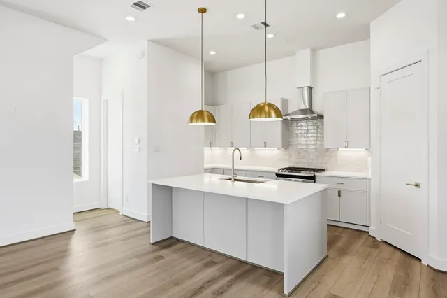 a kitchen with stainless steel appliances granite countertop a sink a stove and a wooden floors