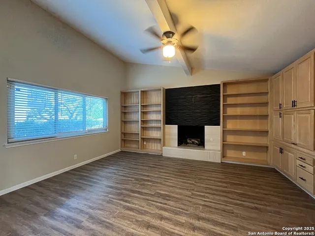 a living room with stainless steel appliances kitchen island hardwood floor and ceiling fan