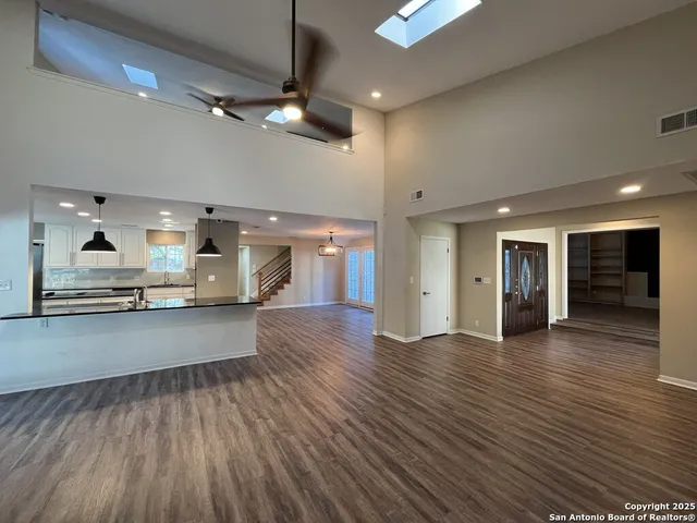 a view of an empty room with a ceiling fan and wooden floor