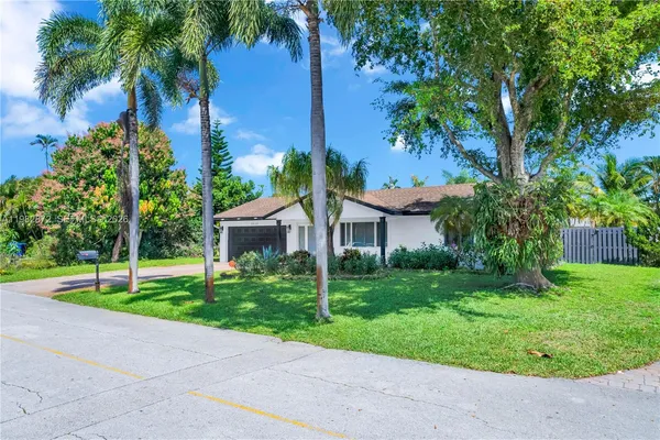 a view of a house with a big yard plants and palm trees