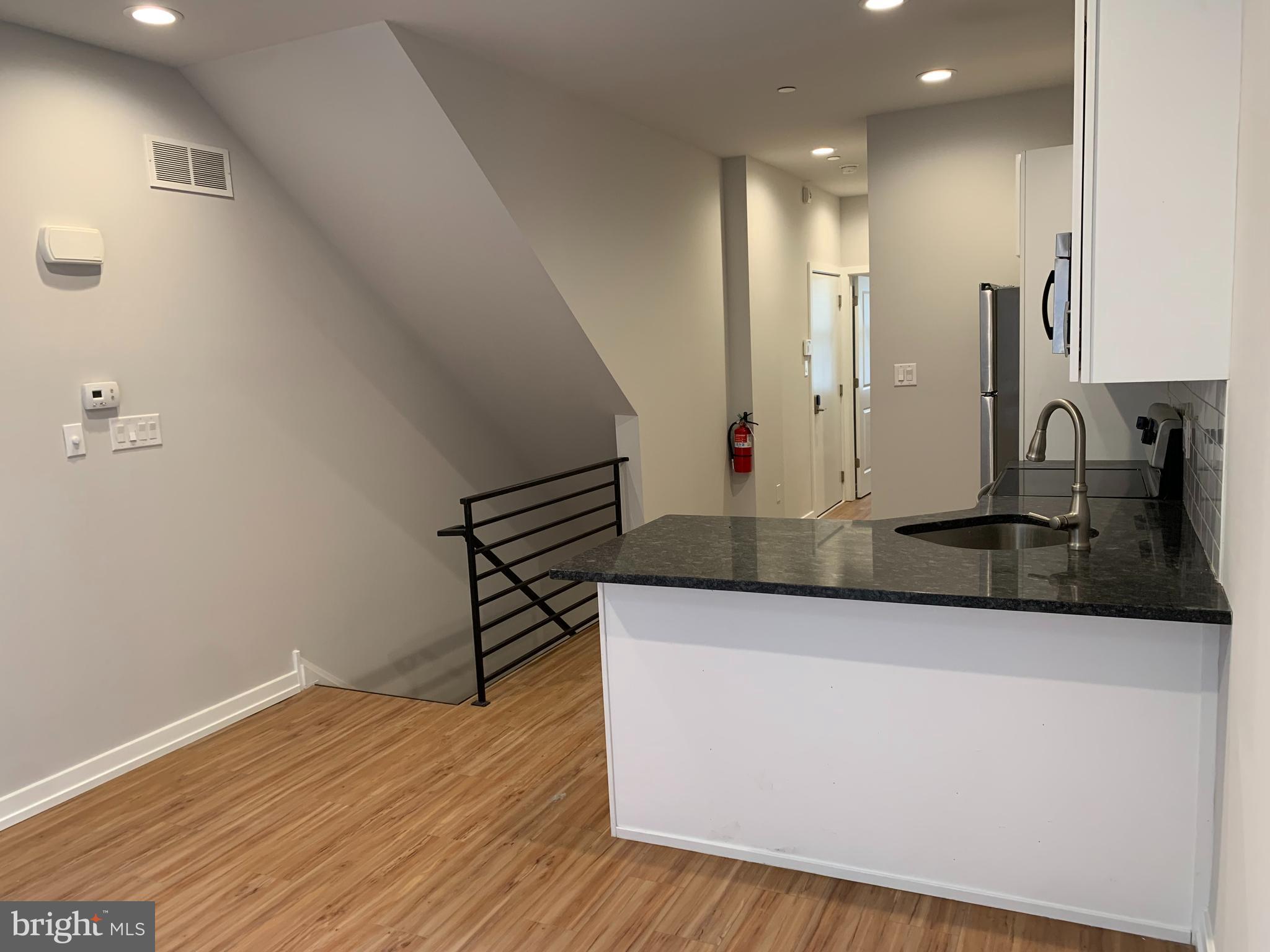 1268 South 27th Street, Unit 1 Philadelphia, PA 19146 - Photo 1 of 26 a view of a kitchen with kitchen island a sink wooden floor and glass door