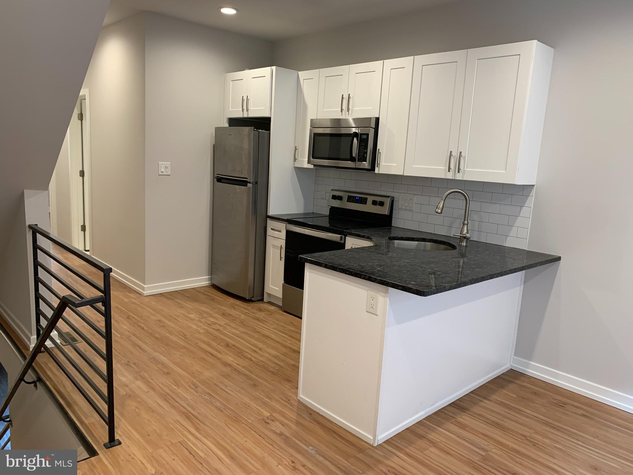 1268 South 27th Street, Unit 1 Philadelphia, PA 19146 - Photo 4 of 26 a kitchen with granite countertop a refrigerator stove and microwave