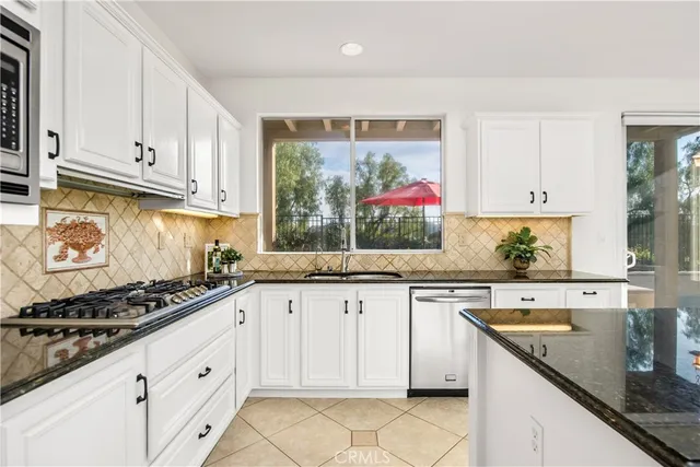a kitchen with granite countertop stainless steel appliances a stove sink and cabinets