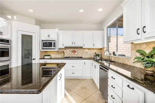 a kitchen with granite countertop white cabinets and stainless steel appliances