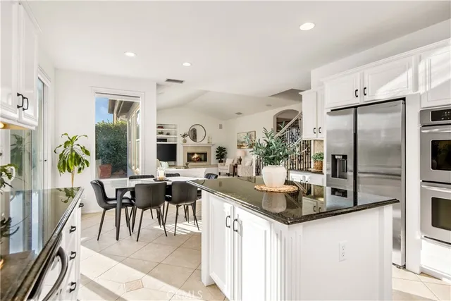 a kitchen with stainless steel appliances kitchen island granite countertop a table chairs and a refrigerator