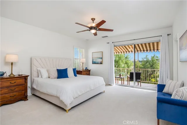 a bedroom with a large bed and a chandelier fan