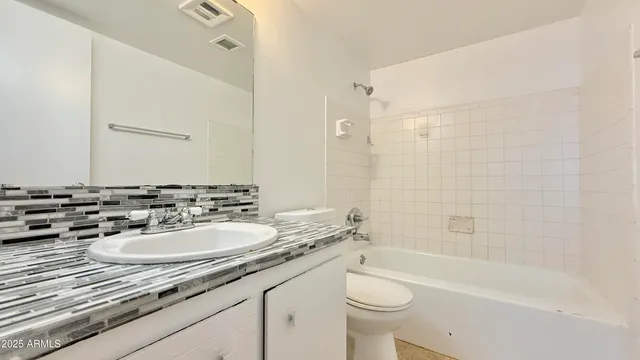 a bathroom with a granite countertop sink a toilet a mirror a bathtub and shower