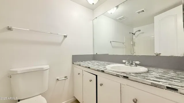 a bathroom with a granite countertop sink a toilet and a mirror