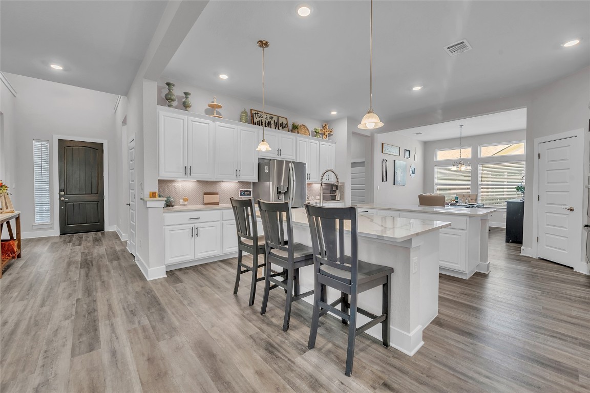 52 Rancho Trail Georgetown, TX 78628 - Photo 1 of 1 Kitchen with white cabinets, hanging light fixtures, a breakfast bar, backsplash, and recessed lighting