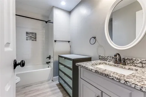 a bathroom with a granite countertop sink a toilet and bathtub