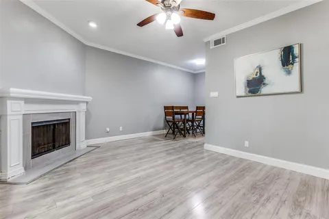 a view of an empty room with wooden floor a fireplace and a window