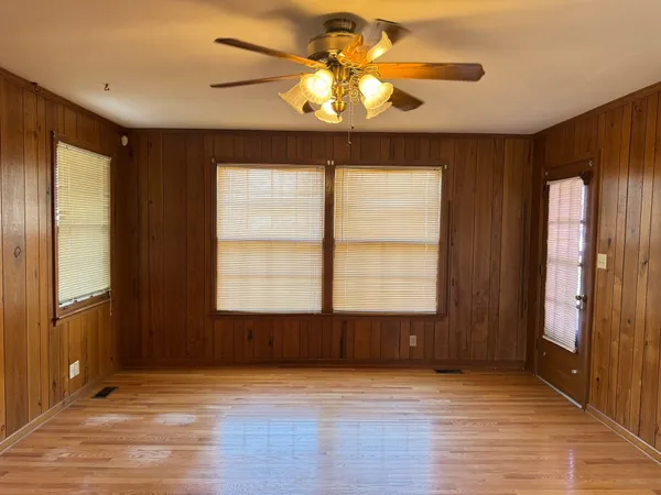 a view of an empty room with window and wooden floor