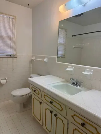 a bathroom with a granite countertop toilet sink and mirror