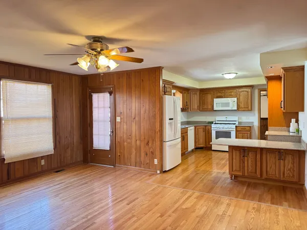 a view of a kitchen with stainless steel appliances granite countertop a refrigerator a sink dishwasher a stove and a dining table with wooden floor