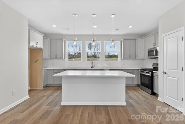 a large kitchen with stainless steel appliances a large counter top a stove a refrigerator and a sink