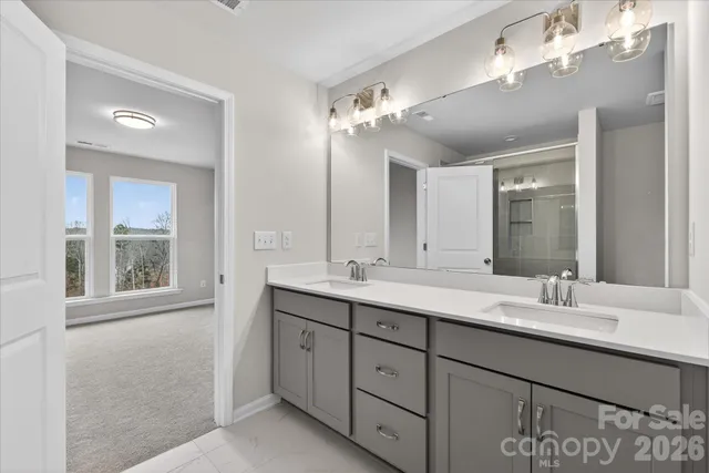 a bathroom with double vanity sinks a vanity a lamp and a mirror