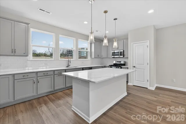 a large white kitchen with a large window a sink and stainless steel appliances