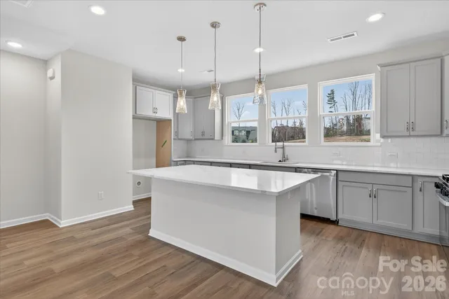 a large kitchen with stainless steel appliances kitchen island granite countertop a sink a window and a counter space