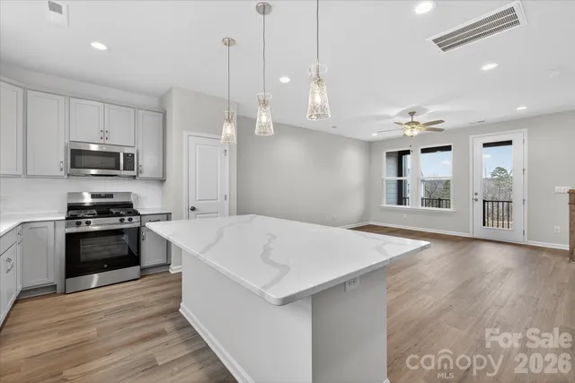 a large white kitchen with a stove a sink dishwasher and a refrigerator with wooden floor