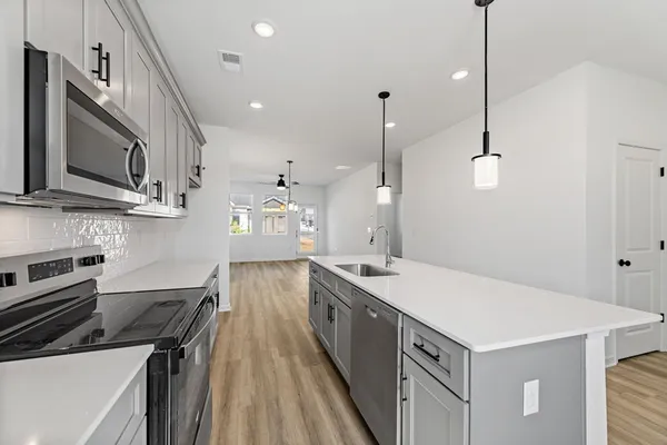 a kitchen with stainless steel appliances granite countertop a sink a stove and a wooden floors